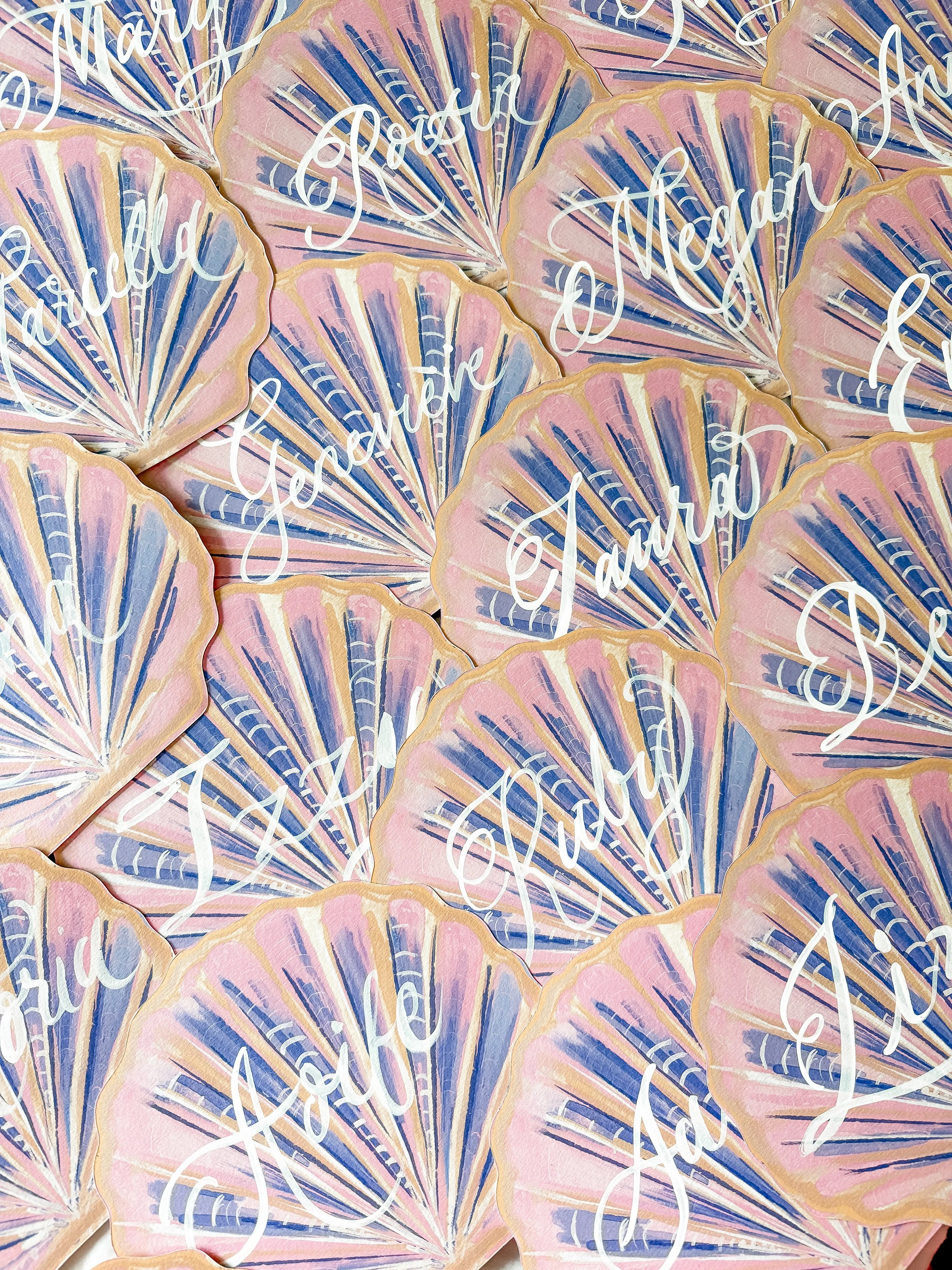 Multiple pastel-colored seashell-shaped paper tags with the words 'Thank You' written in white cursive.