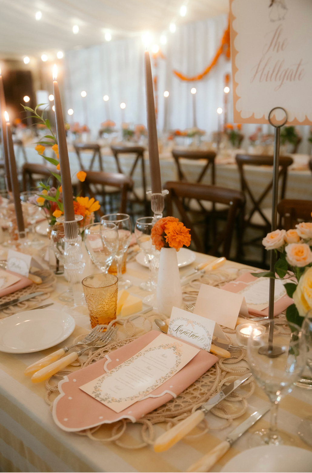 Elegant wedding reception table decorated with peach and orange flowers, candles, glassware, and pink napkins, with a sign reading 'Table 11' and a detailed menu card.