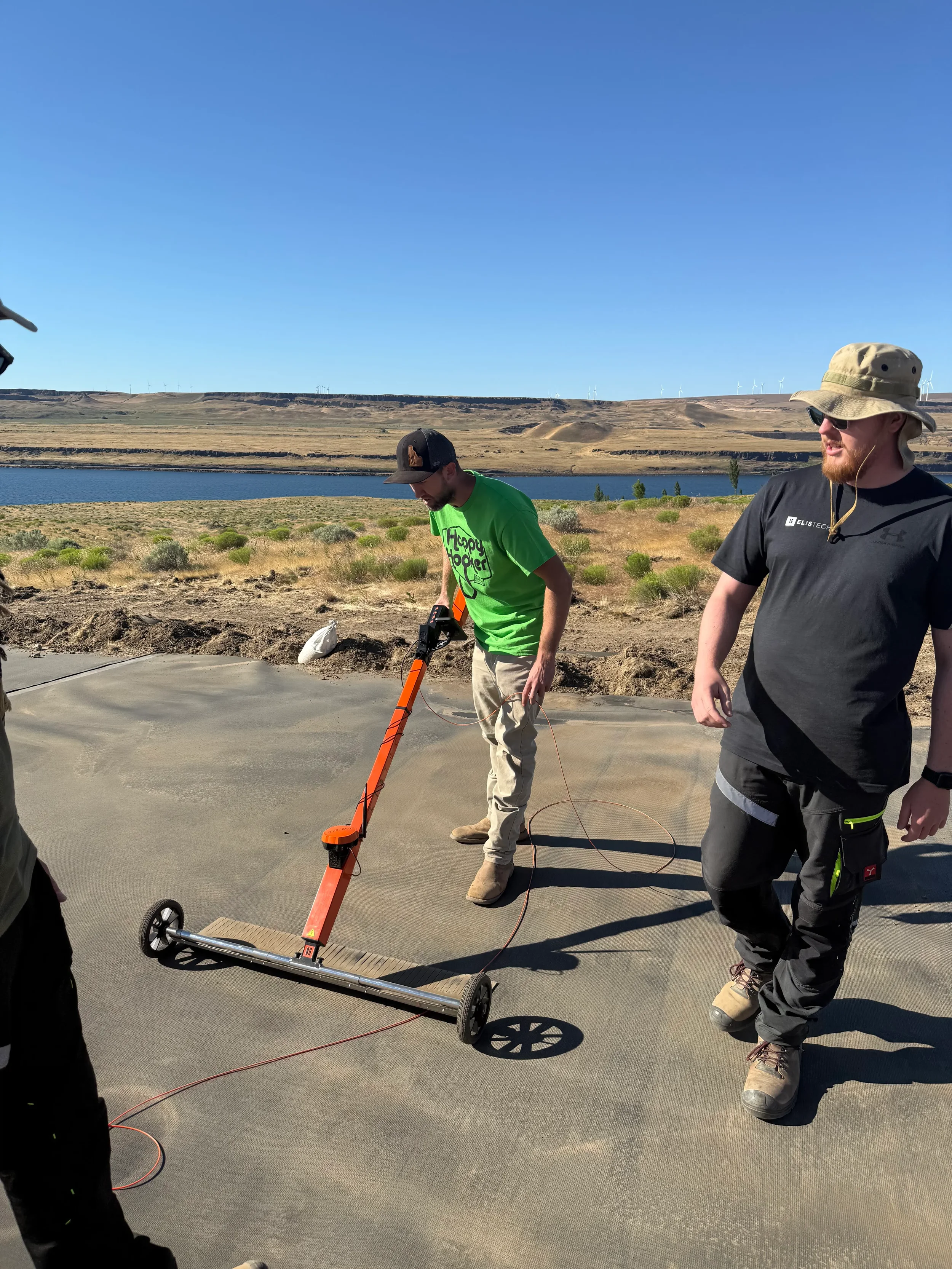 Geosynthetic Advisors technicians performing an electrical leak location survey on a geomembrane liner with a mobile detection cart