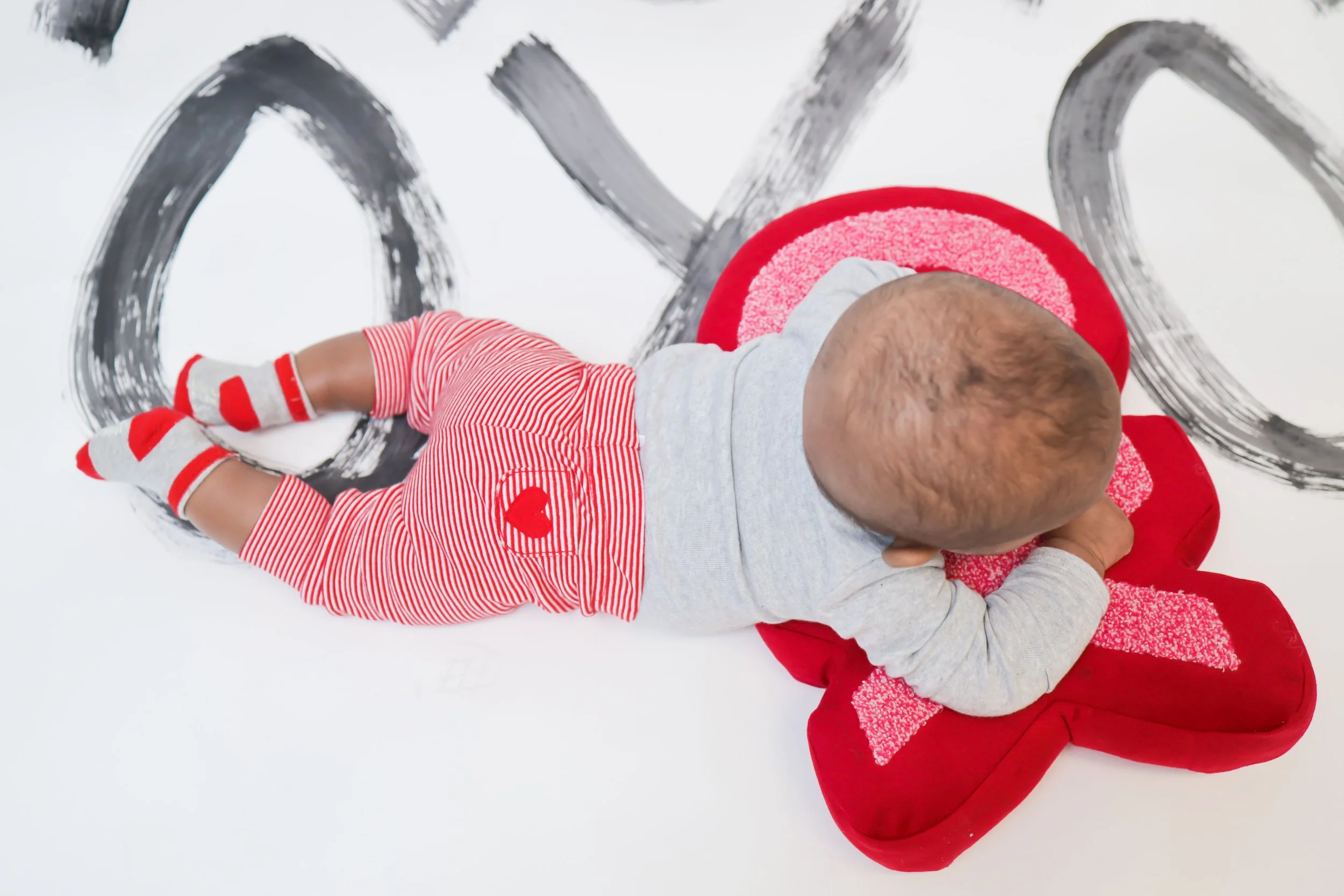 A baby in tummy time on pillow for grant funded developmental playgroup