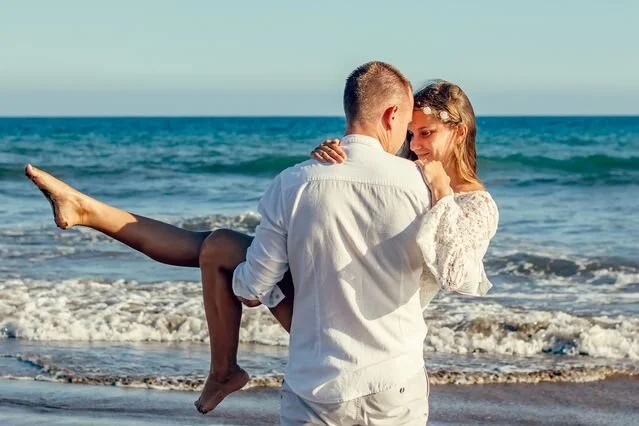 Happy couple laughing together on the beach, showing a healthy relationship built by a better partner
