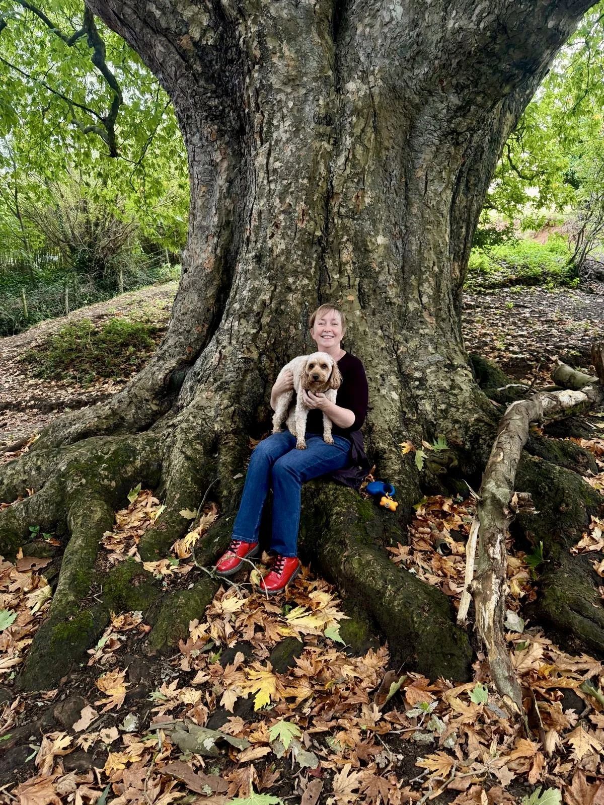 Nicky Williams with her dog Luca smiling at the camera in the woods