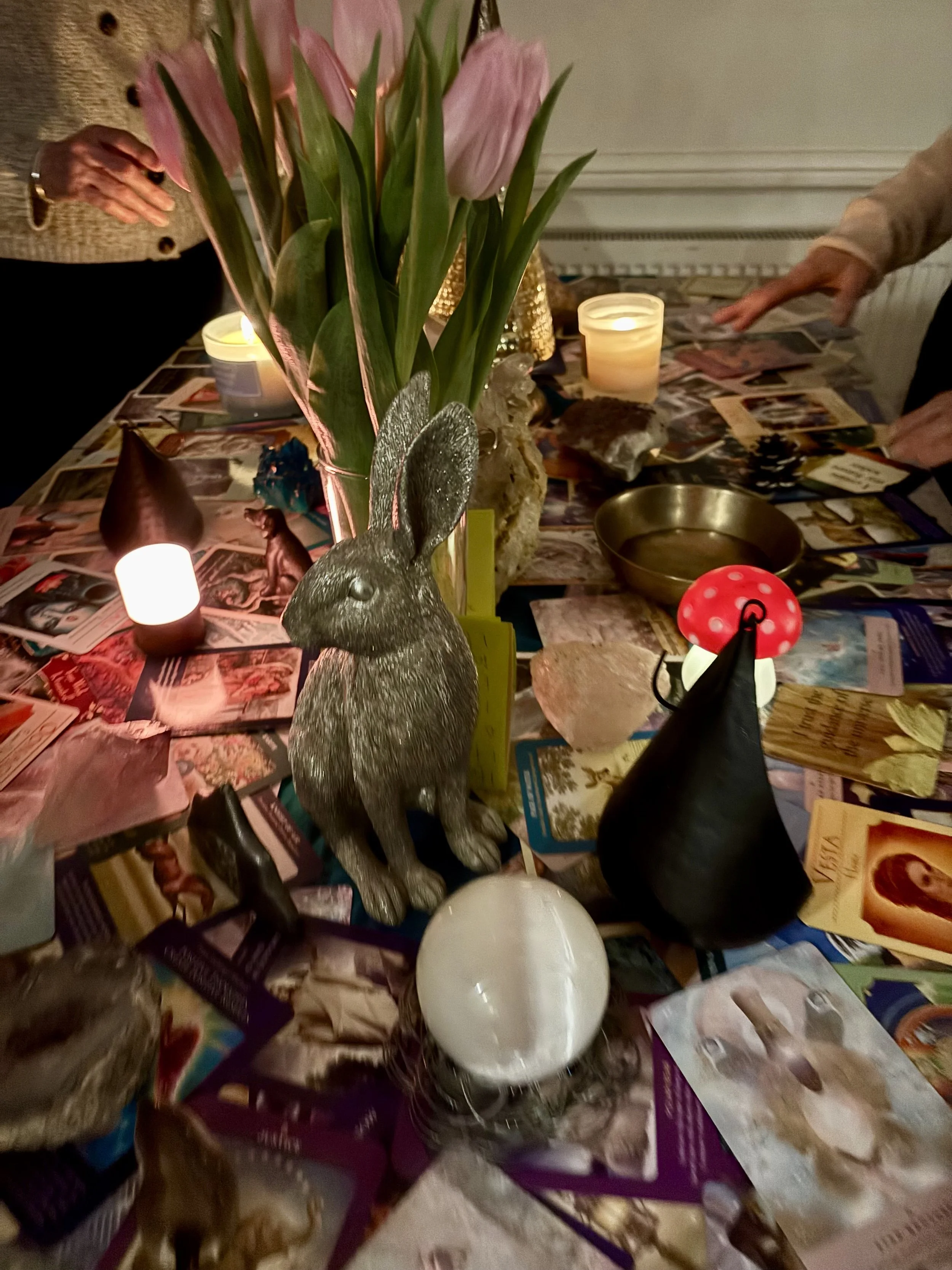 A table covered in Nicky's Angel Cards, crystals, candles, flowers and a brass hare.
