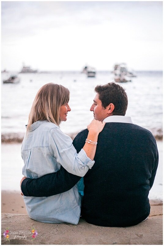  couple looking at one another on the dock at the water 