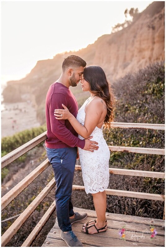  newly engaged couple embracing overlooking the beach 