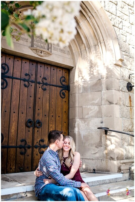  engaged couple embracing as they sit on the steps of the church 