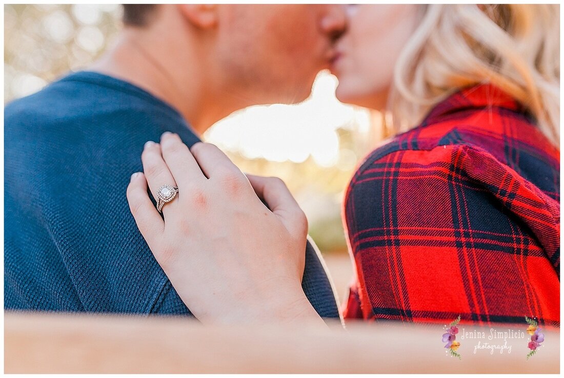  close up of engagement ring resting on husbands shoulder 