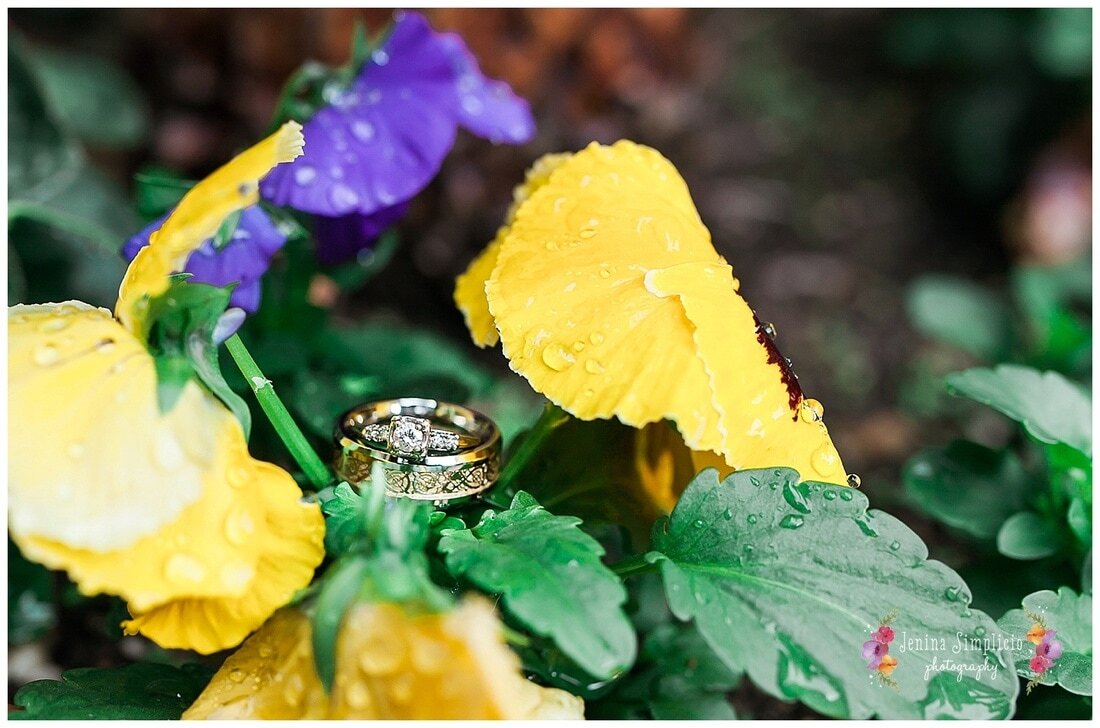  wedding and engagement rings sitting on purple and yellow flowers 