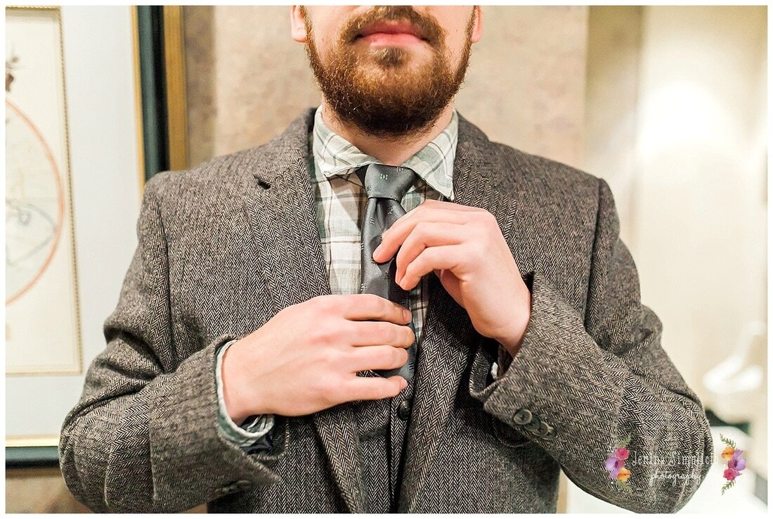  close up of groom fixing his tie 