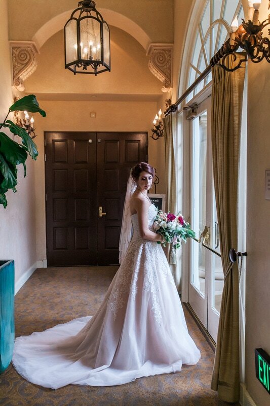  bride standing in front of the windows in her gown 