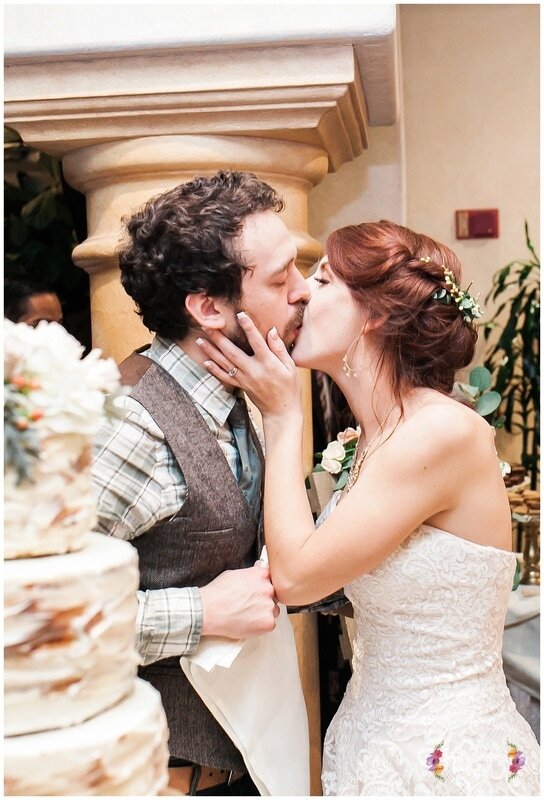  bride and groom kiss in front of the wedding cake 