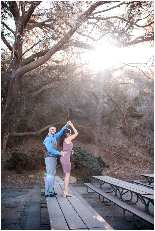  groom to be twirls his bride atop a picnic table 