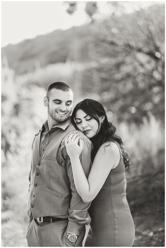  black and white photo of bride to be laying her head on her groom’s shoulder 