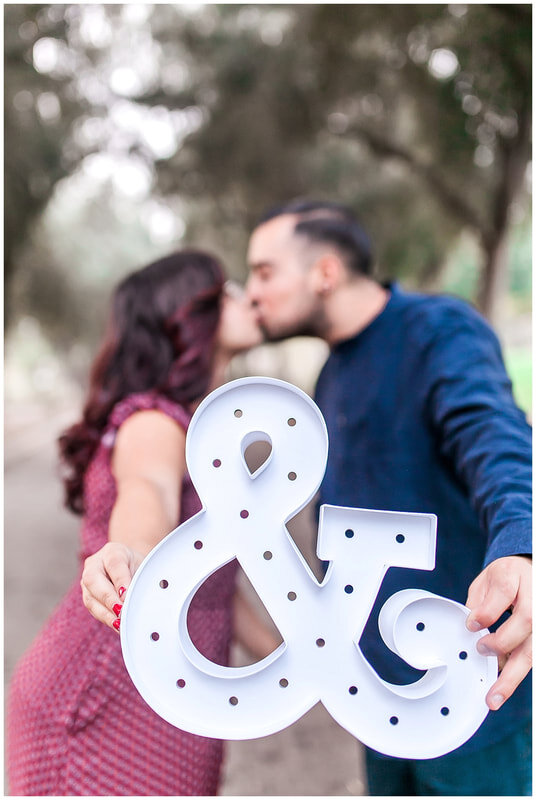  couple kiss behind a sign of the &amp; symbol 