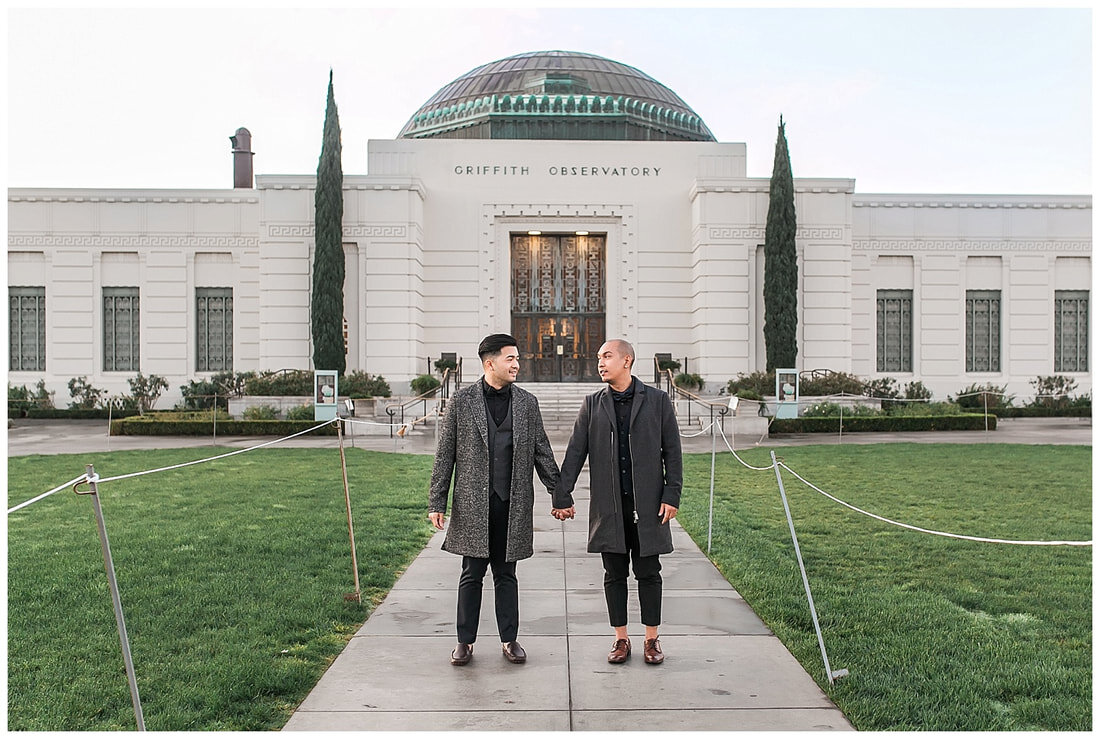 engaged couple holding hands in front of the griffith observatory 
