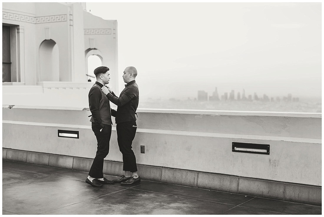  black and white photo of groom fixing his groom’s shirt 