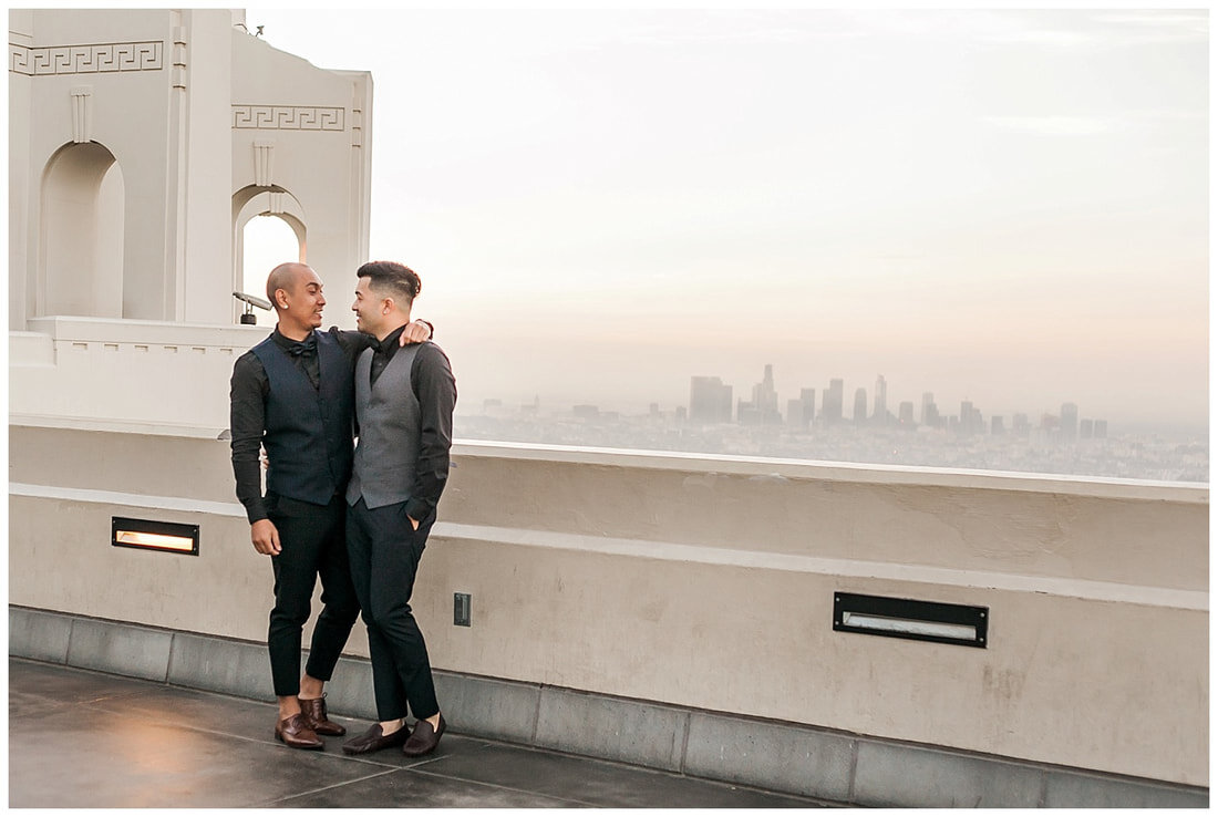  grooms look at one another with the skyline in the background 
