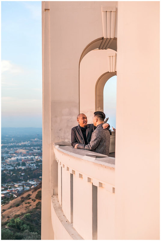  grooms holding one another on the balcony with los angeles in the background 