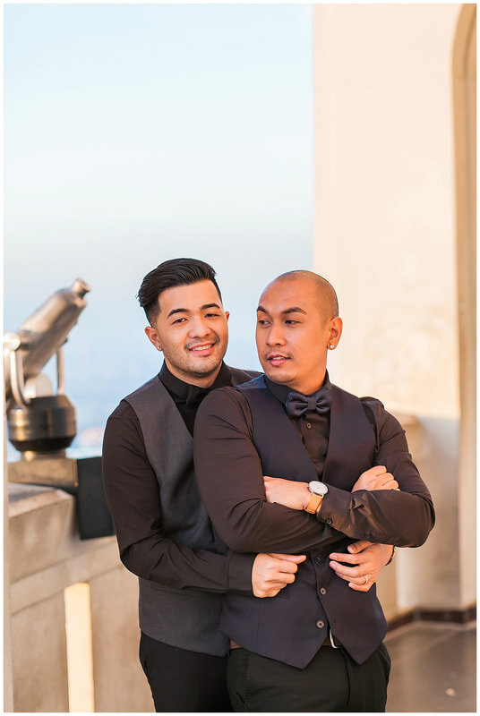  groom is held by his groom around the waist under the archway of the observatory 