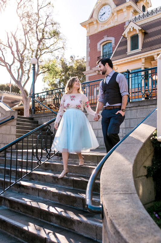  engaged couple walking down the steps in disneyland 