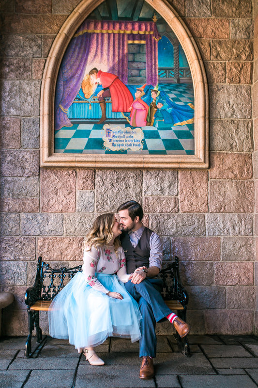  engaged couple about to kiss on a bench below the sleeping beauty mural 