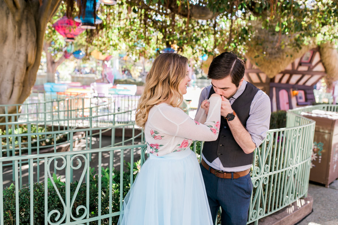  newly engaged groom to be kisses brides hand under lanterns by the teacups 