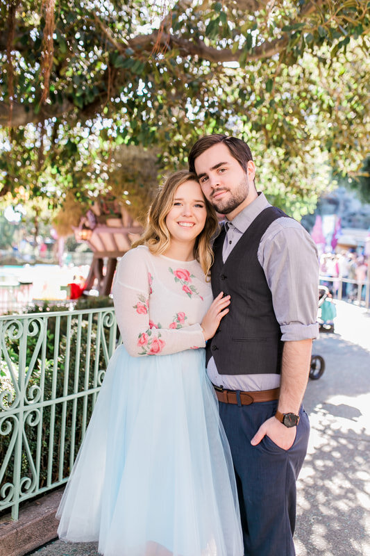  newly engaged couple standing under the trees by the disney teacups 