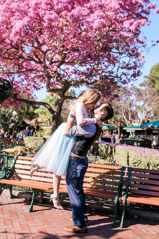  groom lifts his bride to be in front of a cherry blossom tree 