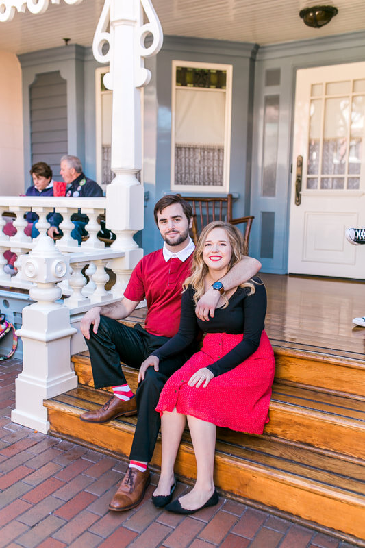  newly engaged couple sitting on the stairs of a house 