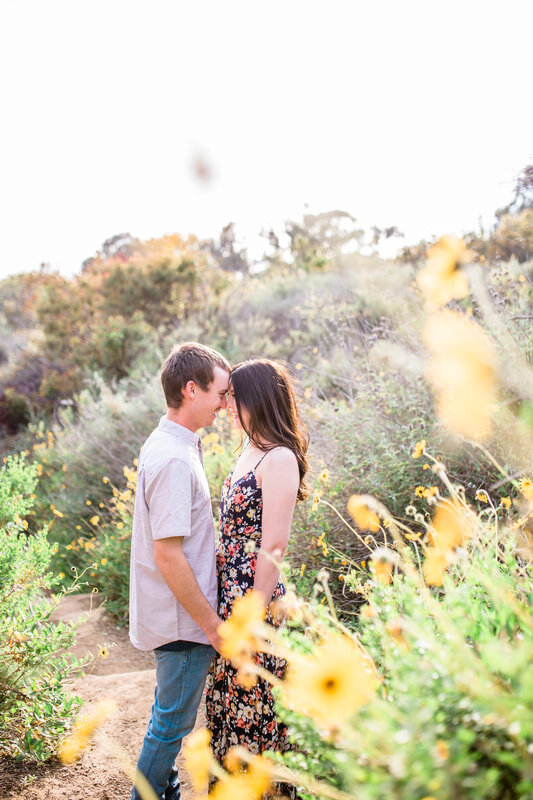  engaged couple smiling at one another among flowers and plants  