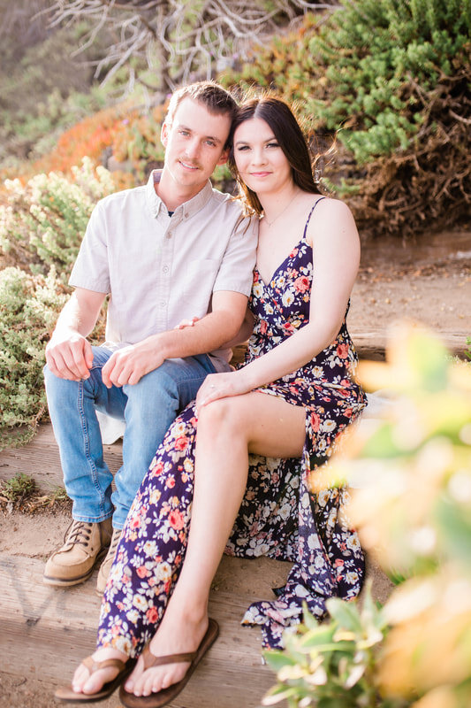  bride and groom to be sitting on wooden steps at the beach 