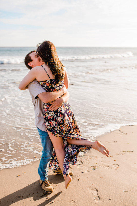  groom lifts his bride and twirls her around on the beach  