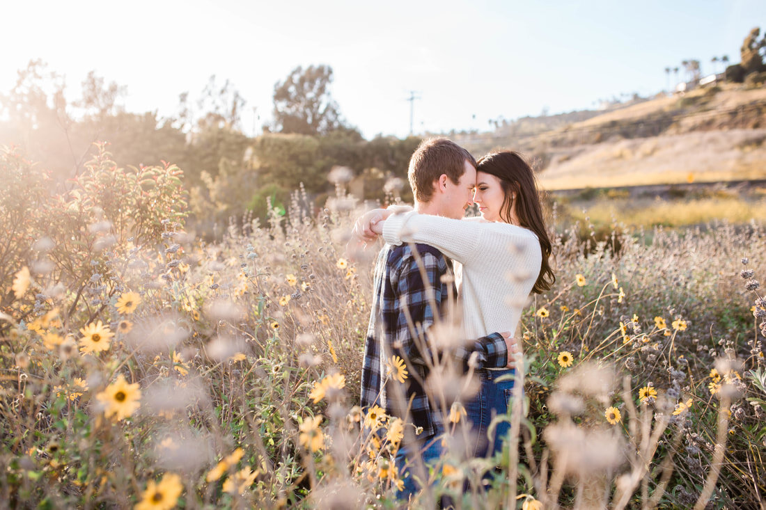  bride and groom with their arms wrapped around one another in the field of flowers by the beach dunes 