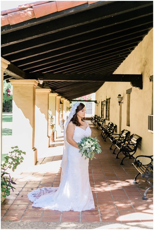  bride standing in the overhand of the venue among the benches and greenery  