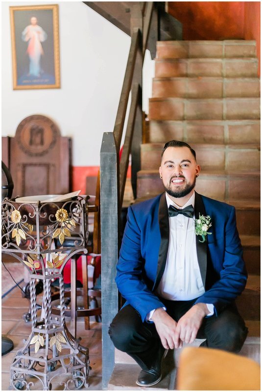  groom smiles and sits on the stairwell in the groom’s suite 