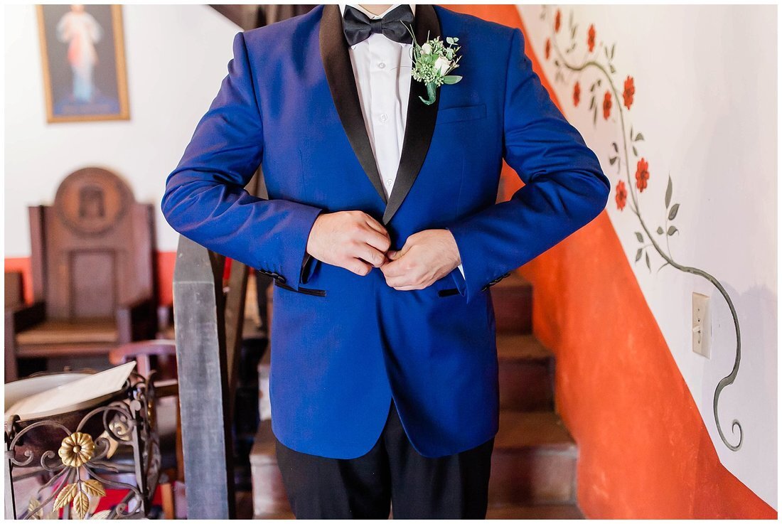  groom fastening the button on his blue tux 