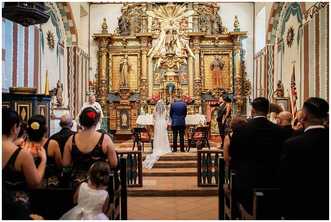  guests stand in the pews of the church and bride and groom stand at the altar 