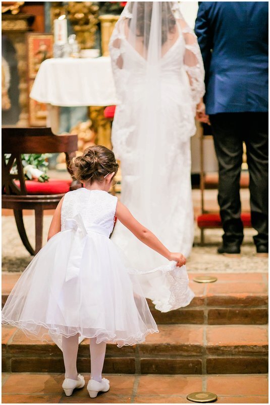  flower girl fixes the brides train on the steps of the church altar 