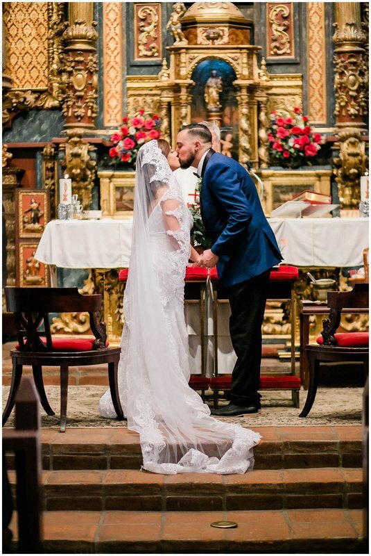  bride and groom kiss at the church altar  