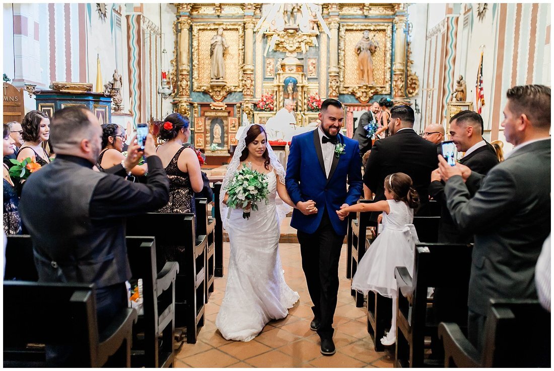  groom grabs flower girl’s hand on his way down the aisle with his bride 