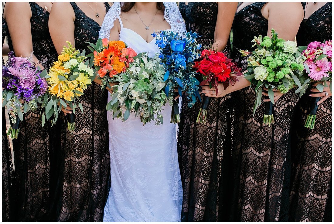  bridal party holding rainbow colored bouquets  