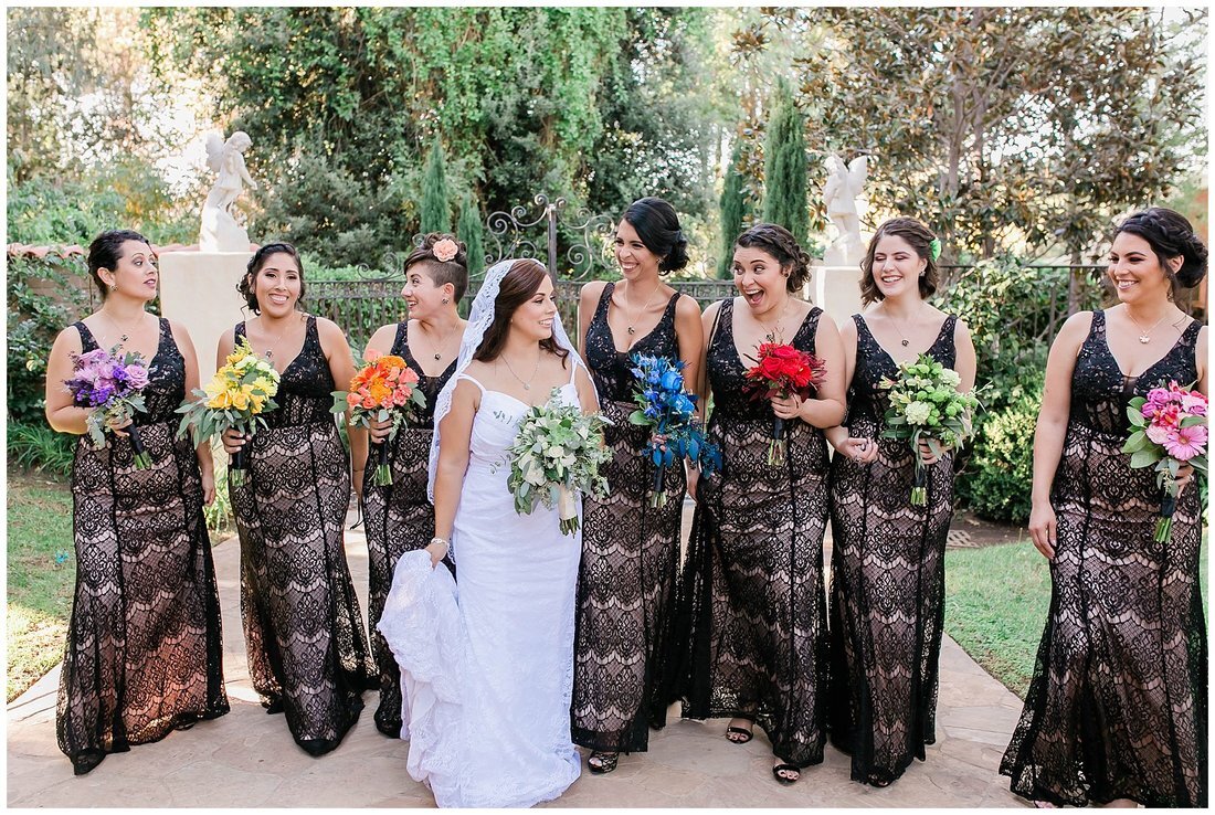  bride stands with her bridal party in front of the garden 