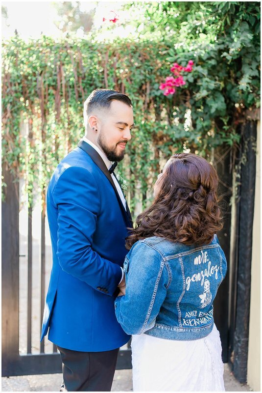  bride and groom holding hands and bride wears a jean jacket with her new name on it 