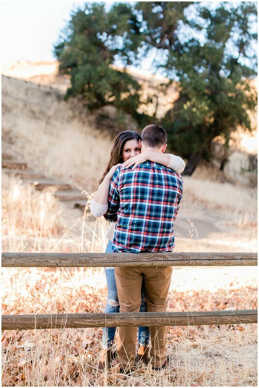  engaged couple together against the fence in the  nature center 