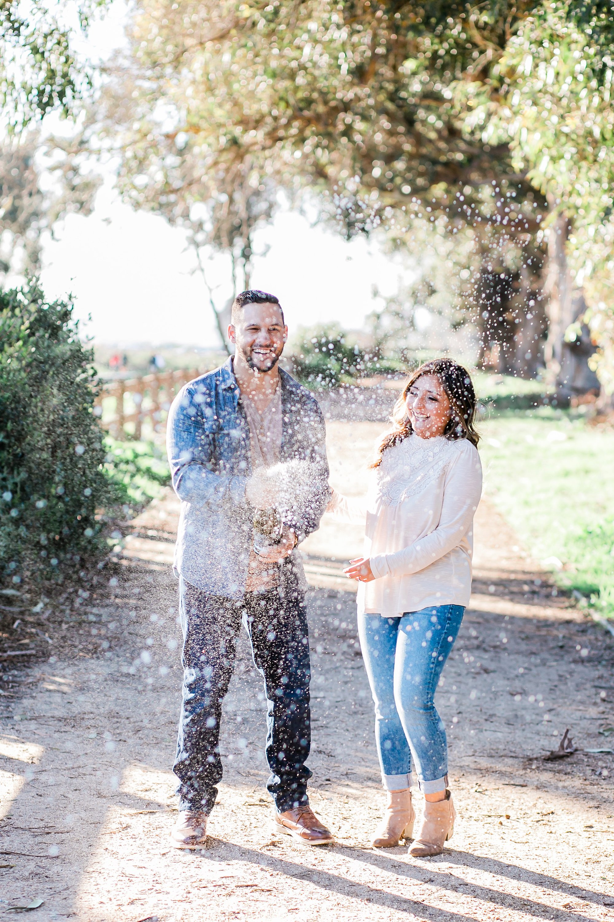  newly engaged couple popping champagne on the garden pathway 