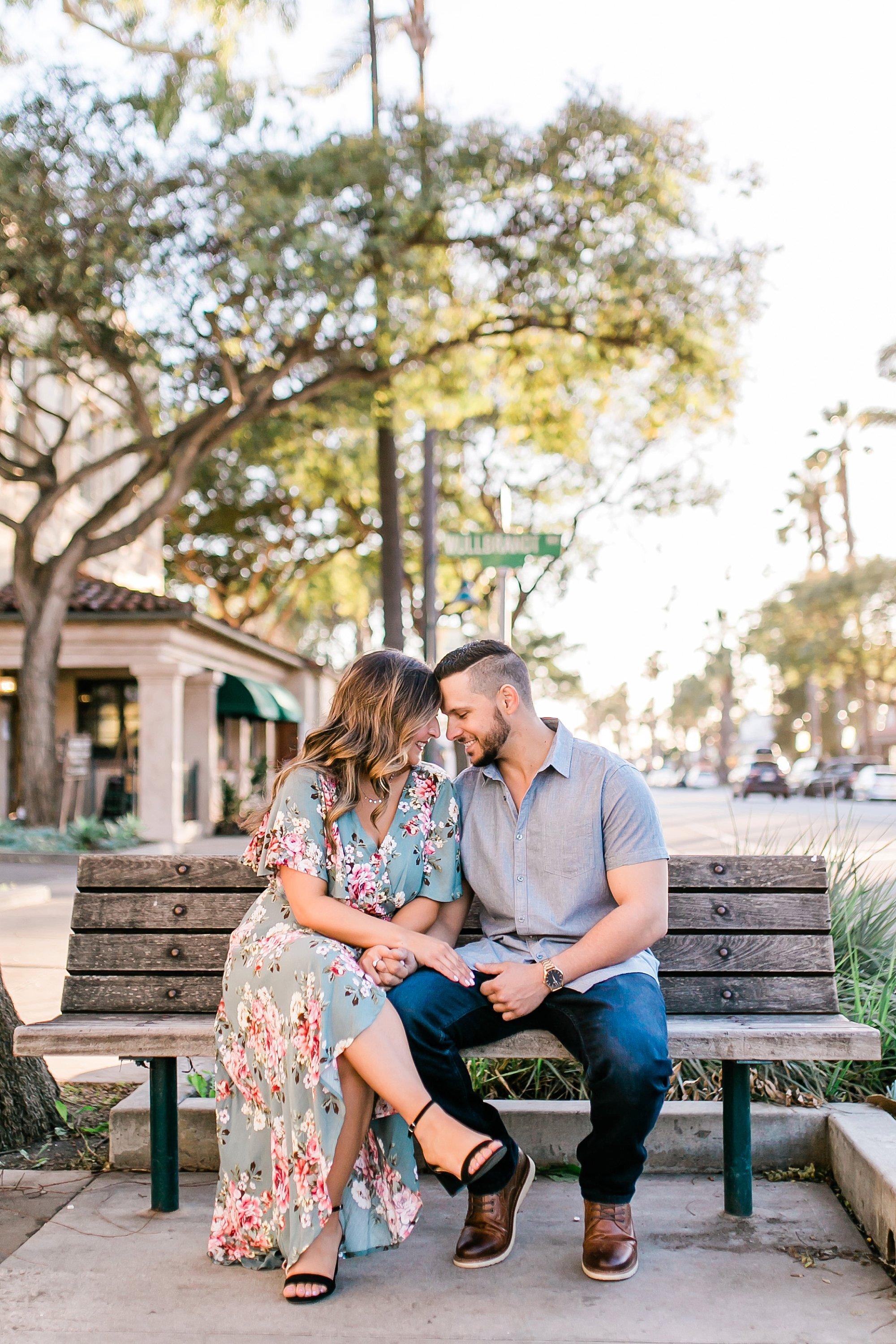  newly engaged couple touching foreheads on the bench 