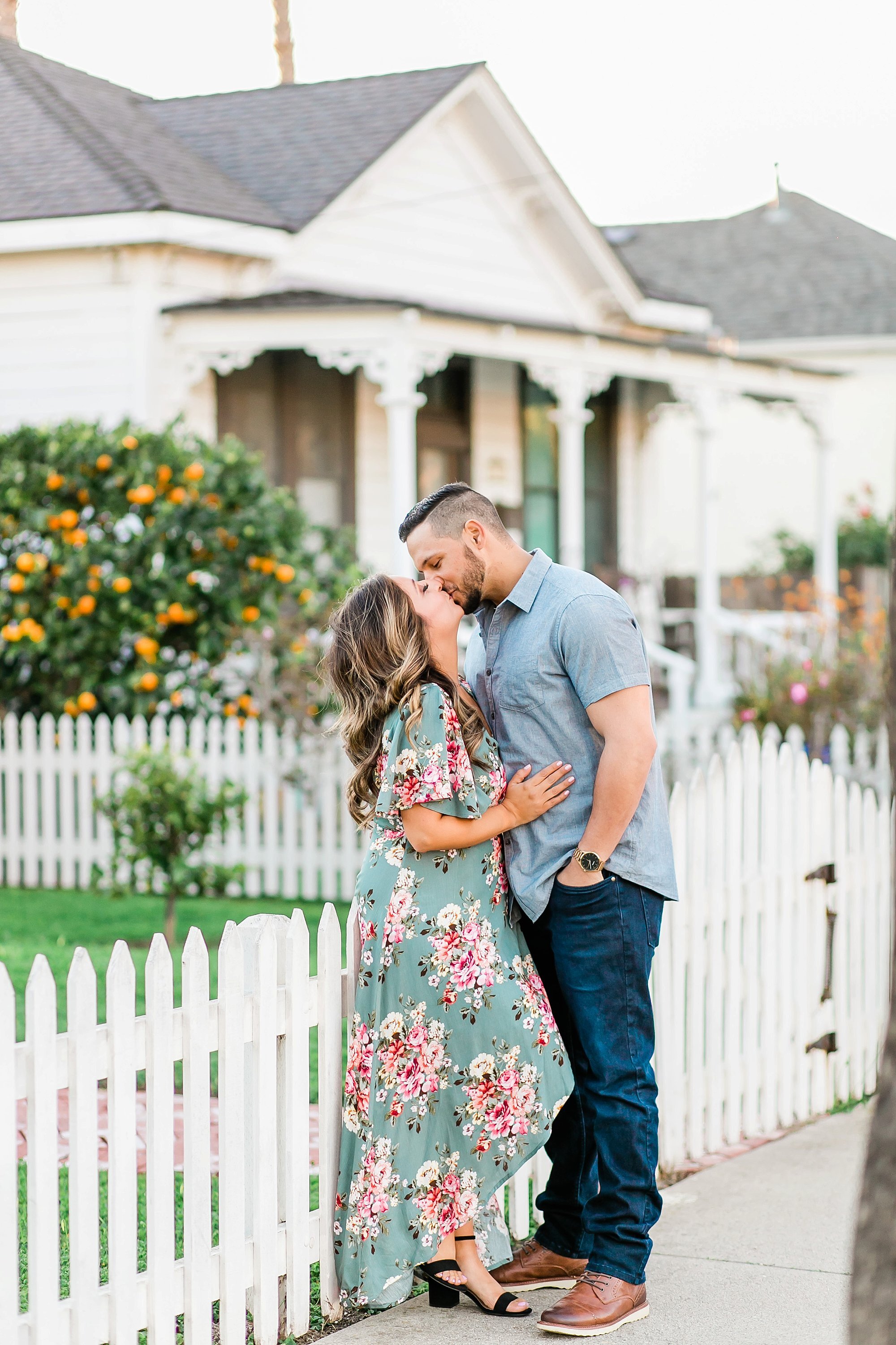  newly engaged couple embracing in front of the white picket fence 
