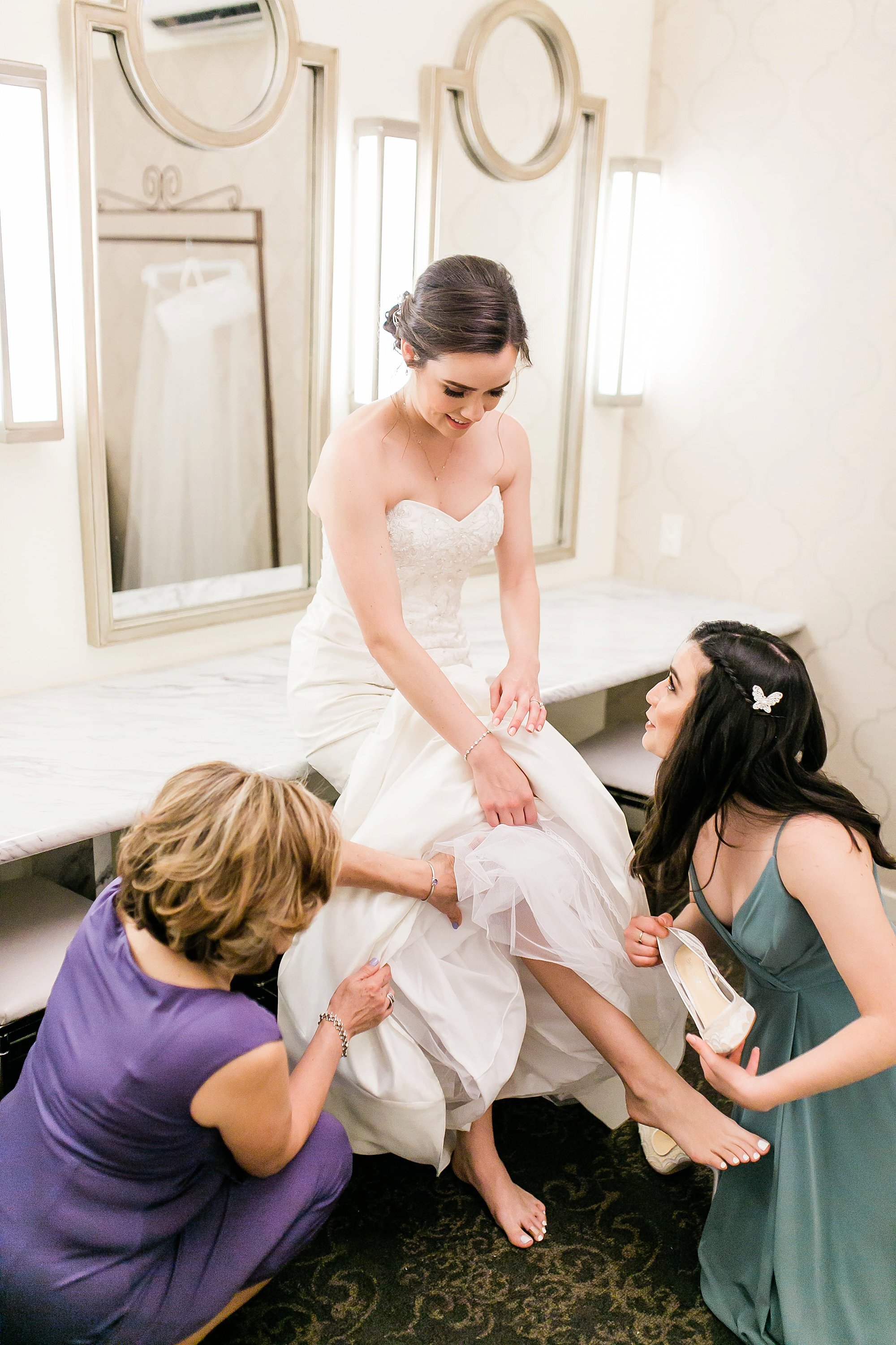  bridesmaids and mother helping bride with her shoes 
