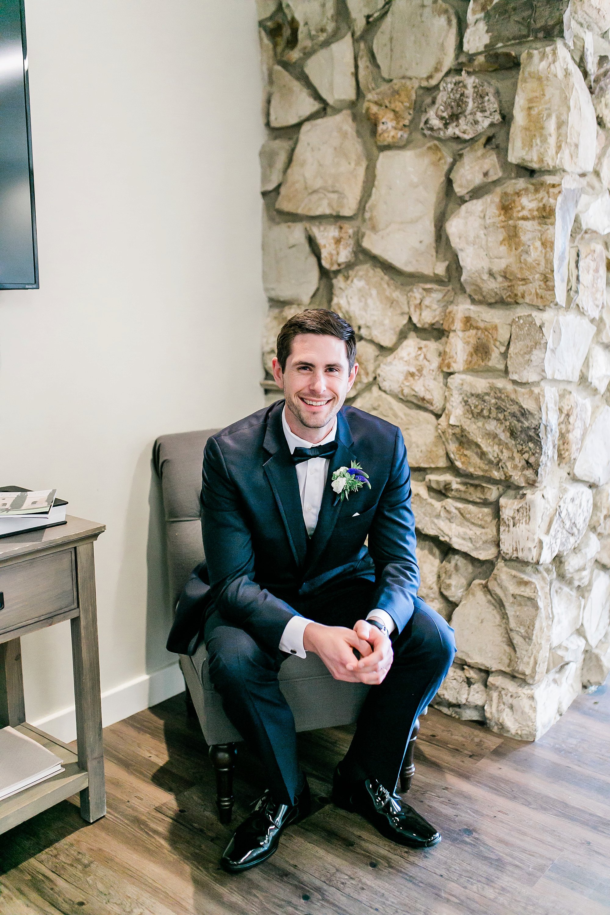  groom sitting in front of stone column 