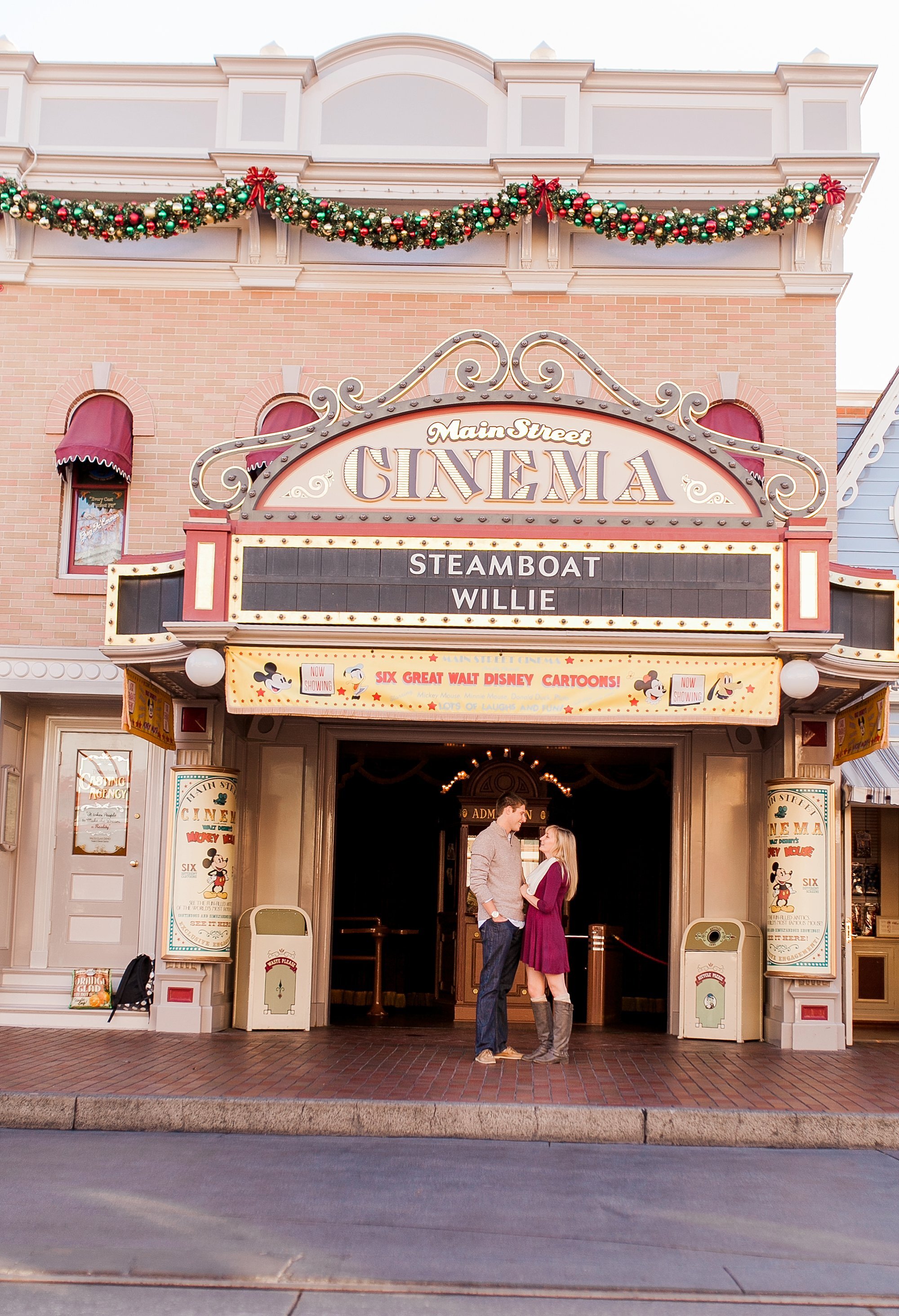  newly engaged couple standing in front of the main street cinema at disneyland 